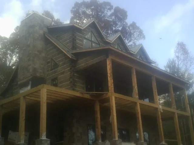 Stone chimney and dormers on a large log home with a timber porch in Garfield