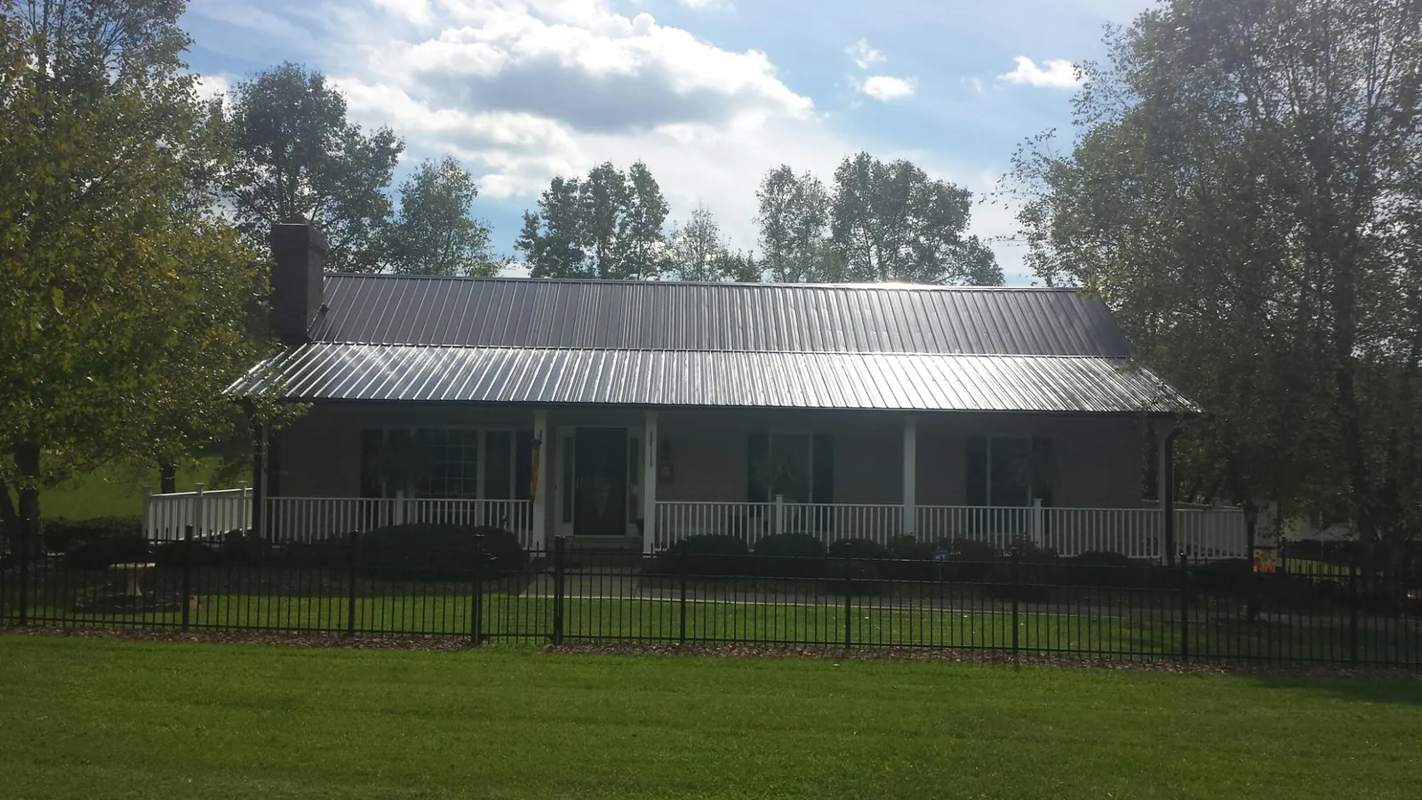 Gray metal roof on a brick ranch with a full width front porch — Gutter Guard Installation work by our crew in Garfield