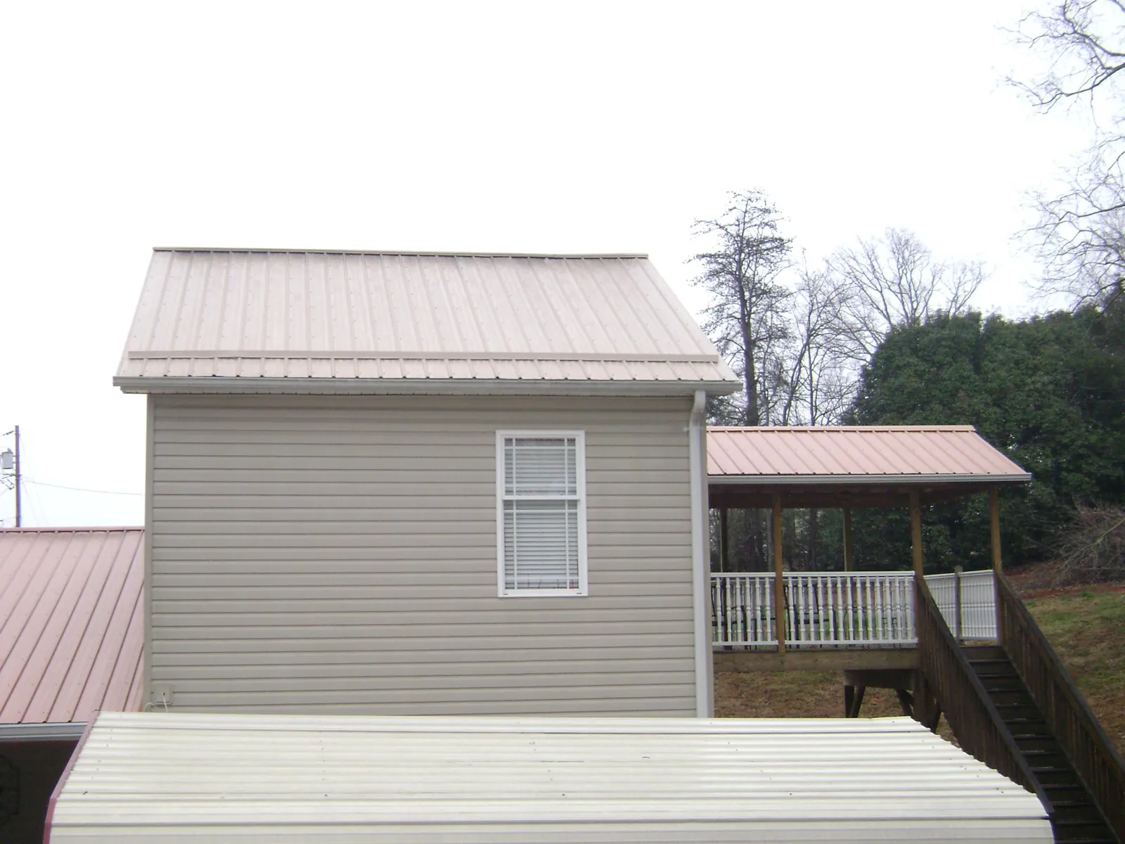 Tan metal roofs on a two story addition and attached porch, from a Roof Replacement job in Garfield